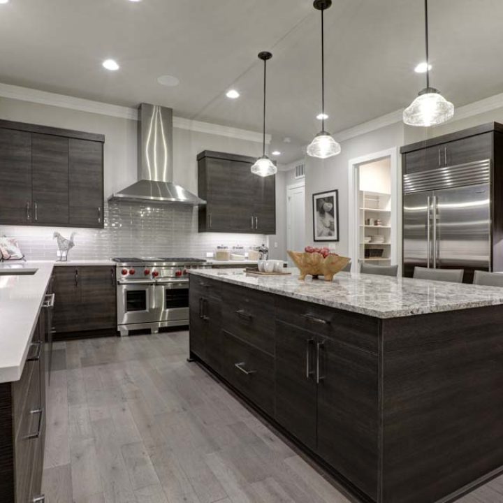 Modern gray kitchen features dark gray flat front cabinets paired with white quartz countertops and a glossy gray linear tile backsplash