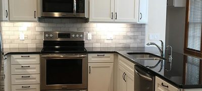 Modern kitchen remodel in Vinings, GA with stainless steel appliances, white cabinets, and black countertops by Custom Professional Remodeling.