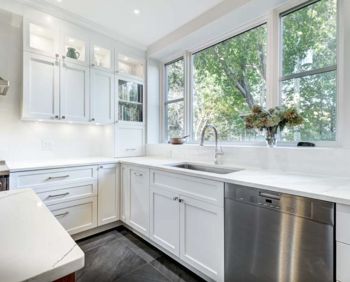 A bright and airy kitchen with white cabinets, a stainless steel stove, a sink, and a window. The abundance of natural light suggests a focus on open space and a connection with the outdoors.